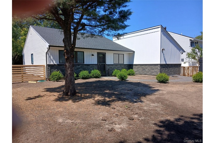 View of front of house with stone siding, roof with shingles, and board and batten siding