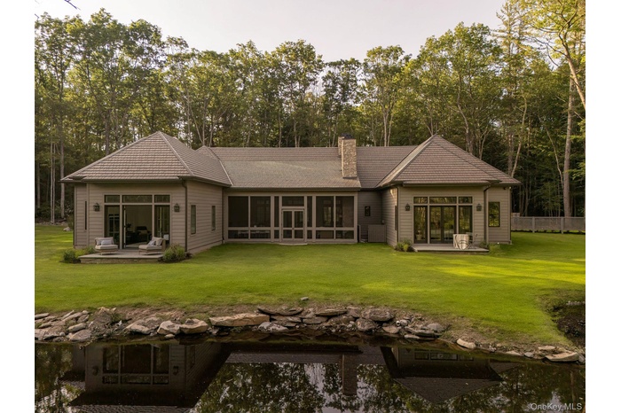Back of house featuring a yard, a chimney, a patio, and a sunroom