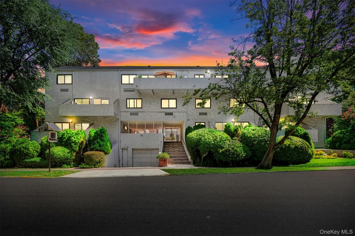 Contemporary COOP with a balcony, an attached garage, concrete driveway, stairs, and stucco siding
