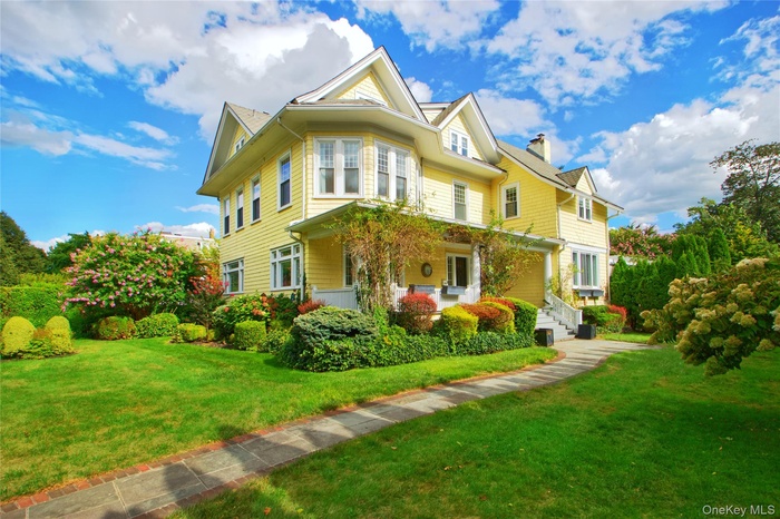 Victorian home with covered porch, a front lawn, and a chimney