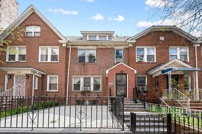 View of front of house with a fenced front yard, a gate, and brick siding