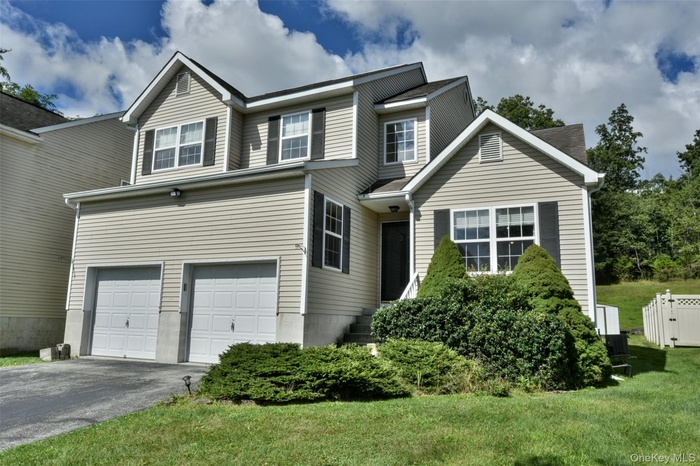 Modern-style home with an attached garage, asphalt driveway, and a front yard