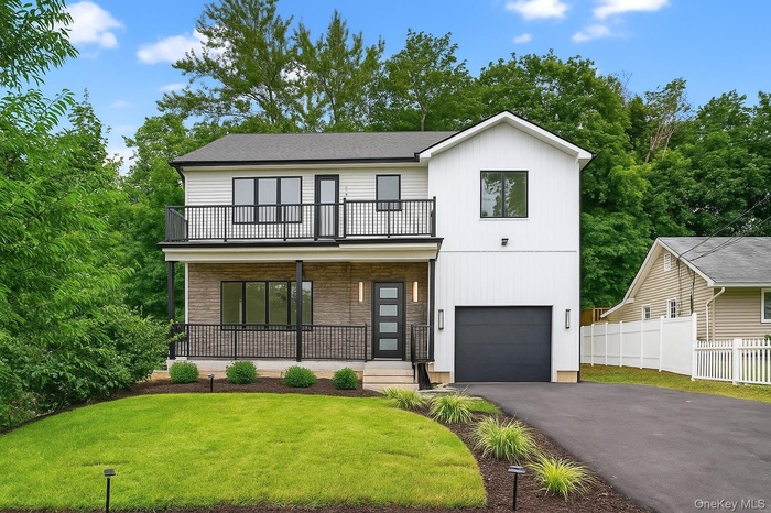 View of front facade featuring driveway, an attached garage, stone siding, and a porch
