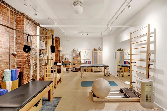 Workout room featuring brick wall, rail lighting, and carpet