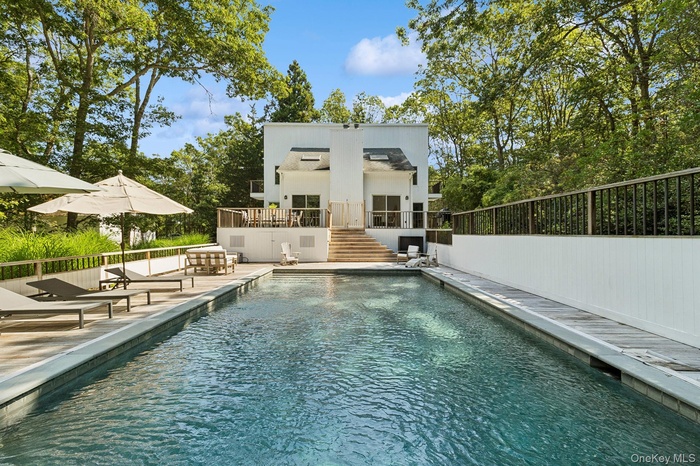 Back of house with a patio area, an outdoor pool, stucco siding, and stairway