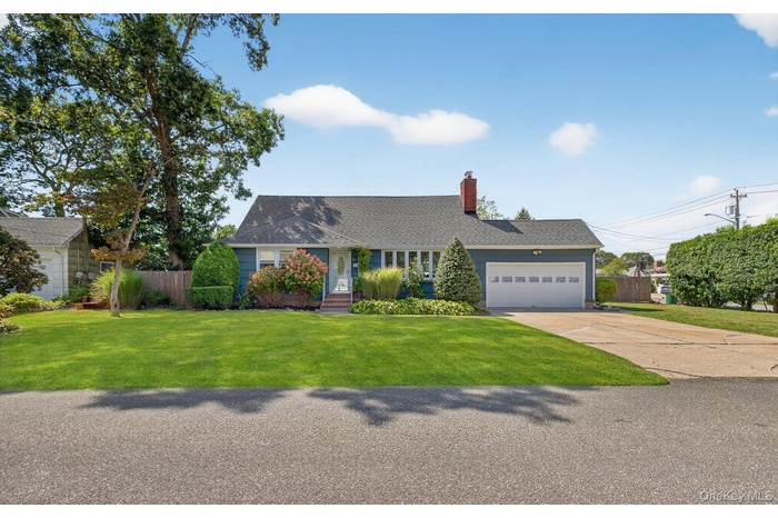 View of front of home featuring a chimney, a garage, driveway, and roof with shingles
