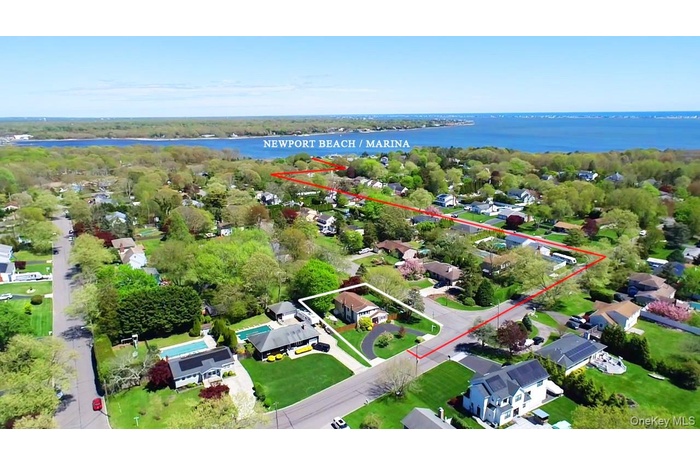 Aerial perspective of suburban area featuring a large body of water and property boundaries highlighted