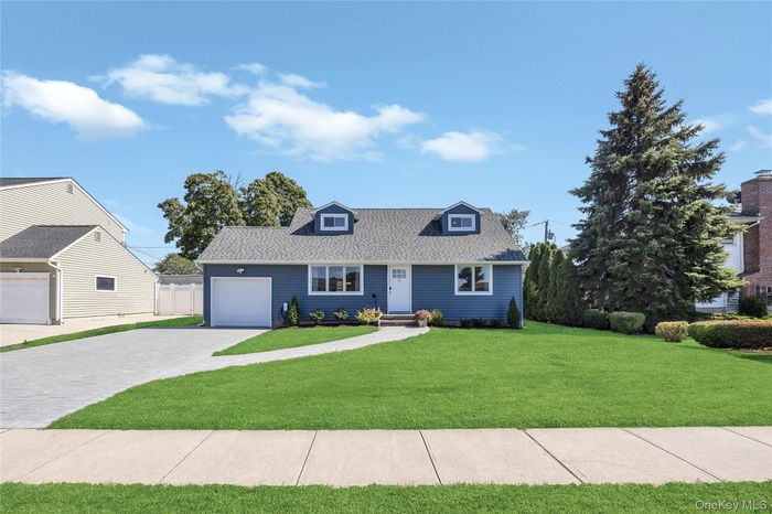 View of front of house with decorative driveway, a front lawn, roof with shingles, and a garage