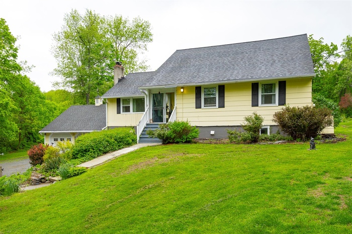 View of front of property featuring a chimney, a front yard, a shingled roof