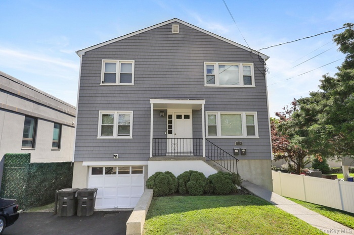 View of front facade featuring stairs, asphalt driveway, and an attached garage