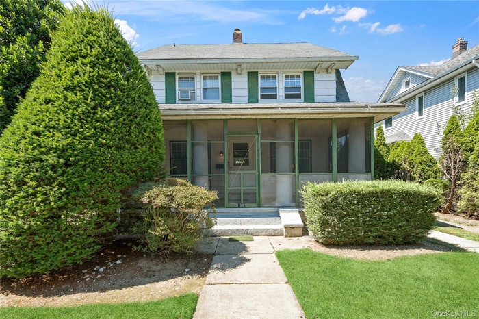 View of front facade featuring a sunroom and a chimney