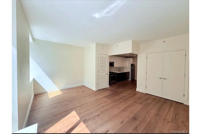 Unfurnished living room featuring wood finished floors and baseboards