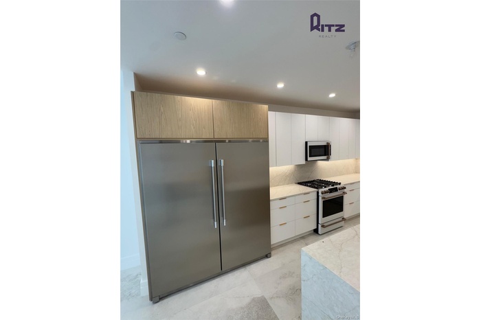 Kitchen with appliances with stainless steel finishes, modern cabinets, light stone counters, and recessed lighting