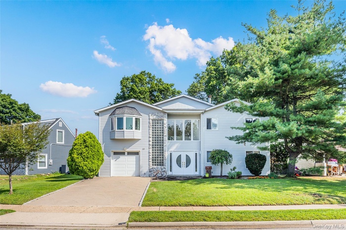 View of front of home with concrete driveway, a front yard, and a garage