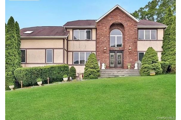 Back of house featuring stucco siding, a lawn, and brick siding
