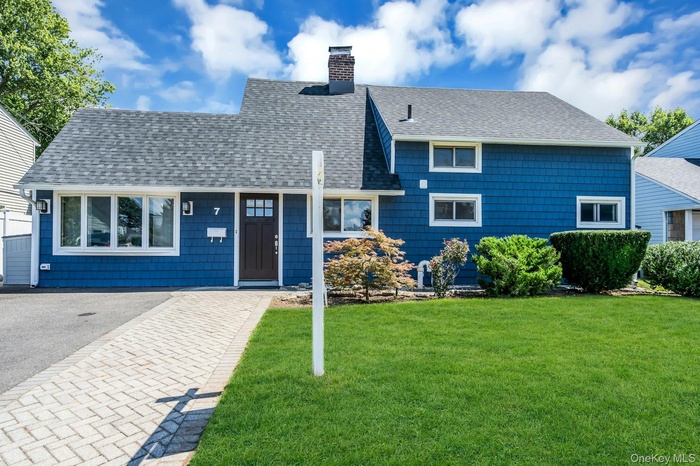View of front of house featuring roof with shingles, a front yard, and a chimney