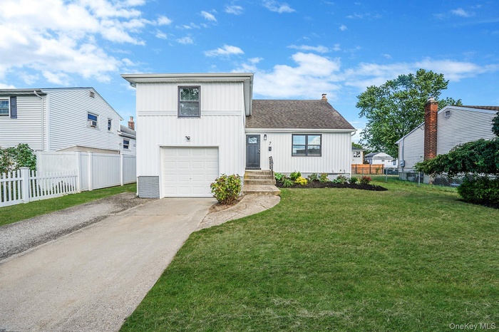 View of front facade with driveway, a shingled roof, and board and batten siding