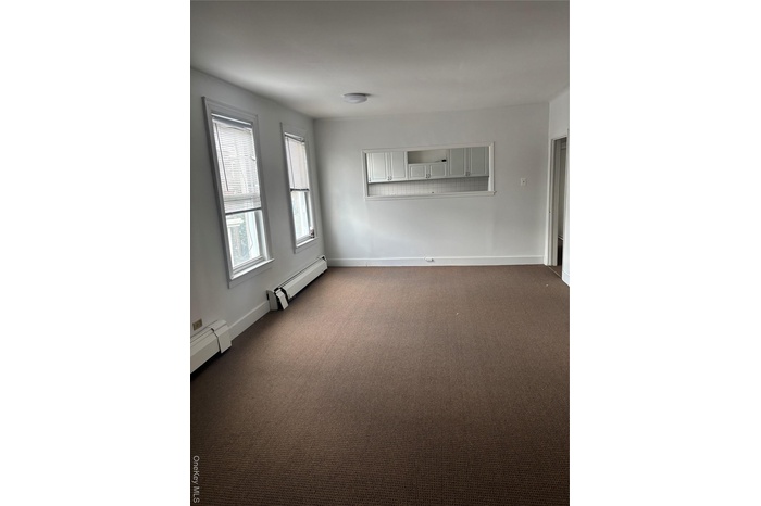 Spare room featuring dark carpet and a baseboard heating unit
