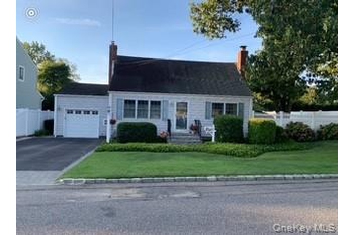 View of front of home featuring asphalt driveway, a garage, and a chimney