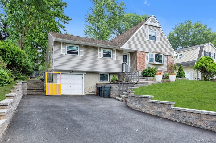 View of front of house featuring asphalt driveway, a front lawn, and a garage