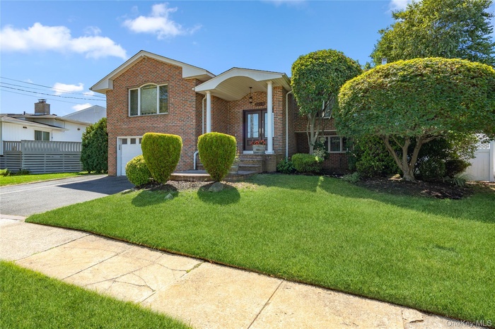 View of front of home featuring asphalt driveway, brick siding, and a garage