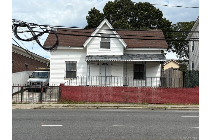 View of front of home with a fenced front yard, a porch, and a shingled roof