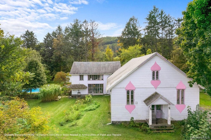 View of front facade featuring a front yard and a wooded view