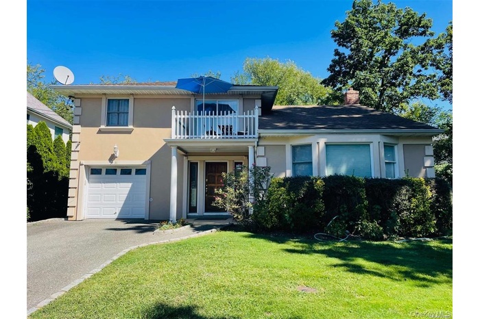 View of front of house featuring a balcony, stucco siding, asphalt driveway, and a garage