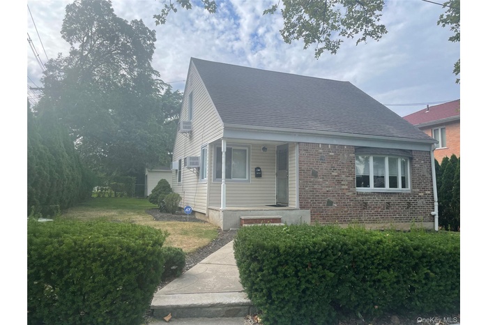 View of front of house featuring covered porch, brick siding, and a shingled roof