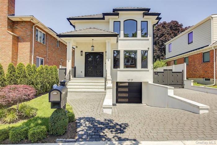 View of front of property with decorative driveway, stucco siding, an attached garage, a gate, and a tiled roof