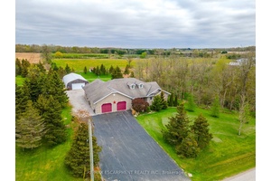 Stunning custom bungalow built in 2005, set on a picturesque 1 acre lot surrounded by open fields, young forest, and a scenic ravine.