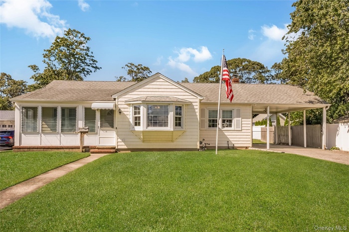 View of front of home with roof with shingles and an attached carport