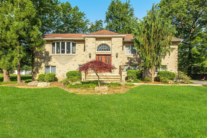 Tri-level home featuring a front lawn and brick siding