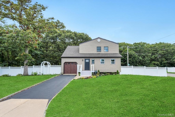 View of front of home featuring a garage, asphalt driveway, and view of wooded area