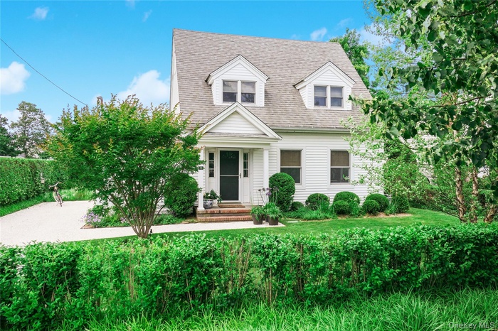 Cape cod-style house with a shingled roof and covered porch