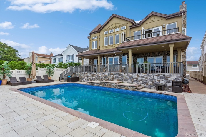 Back of property with a patio area, a fenced in pool, and a balcony