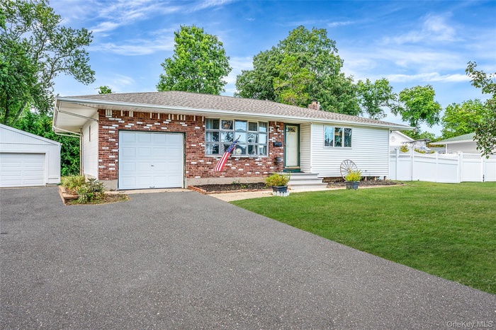Ranch-style home with brick siding, driveway, a chimney, and a garage