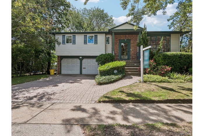 View of front of home with decorative driveway, brick siding, and an attached garage