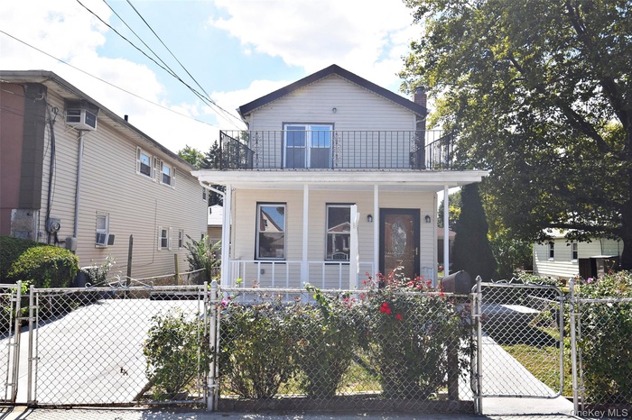 View of front of house featuring a gate, a fenced front yard, a porch, and a chimney