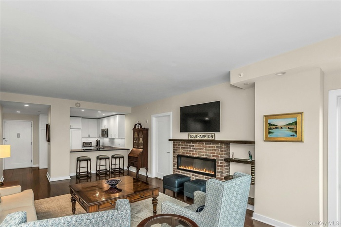 Living room with dark wood-style flooring, baseboards, and a brick fireplace