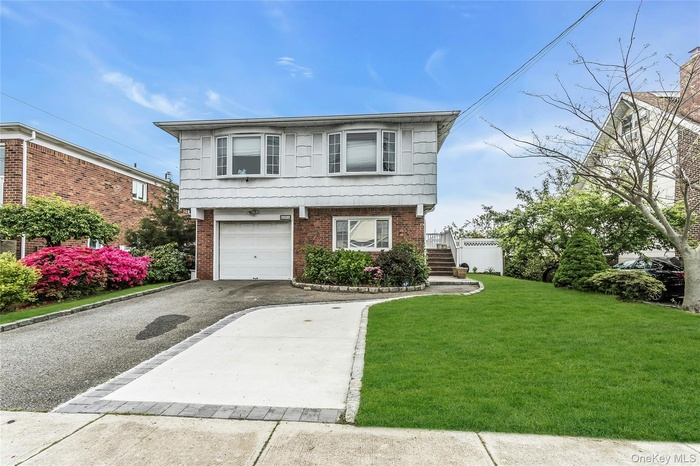 View of front of property featuring driveway, brick siding, an attached garage, and a front yard