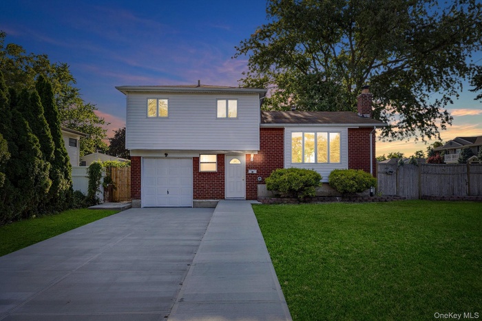 Split level home featuring brick siding, a chimney, concrete driveway, and a garage