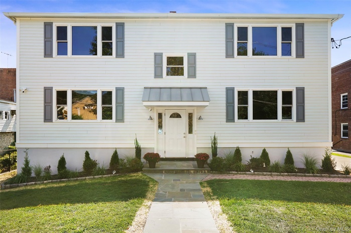View of front of home with a standing seam roof, a front lawn, and a metal roof