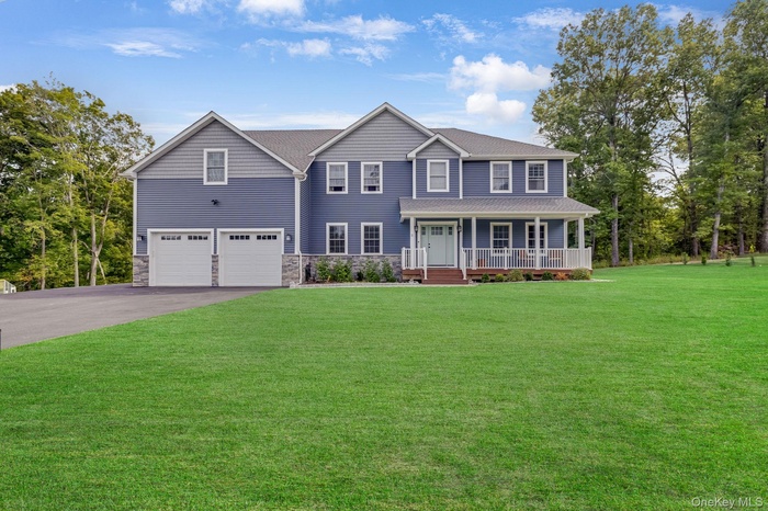 Colonial inspired home featuring covered porch, driveway, a front lawn, and stone siding