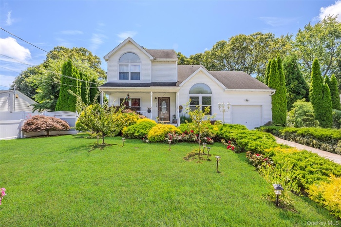Traditional home with covered porch, an attached garage, and roof with shingles
