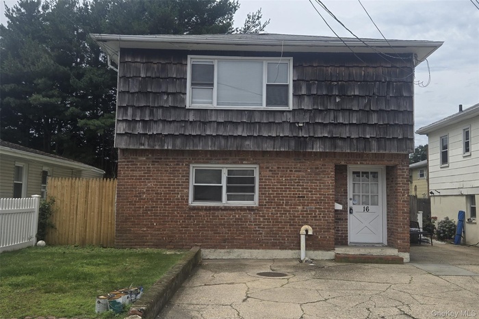 View of front facade with mansard roof, a patio area, and brick siding