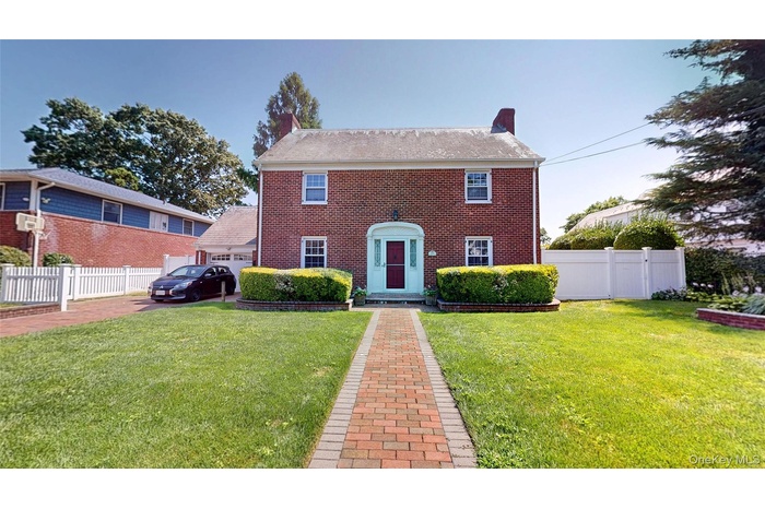 Colonial inspired home with a chimney, brick siding, and a garage