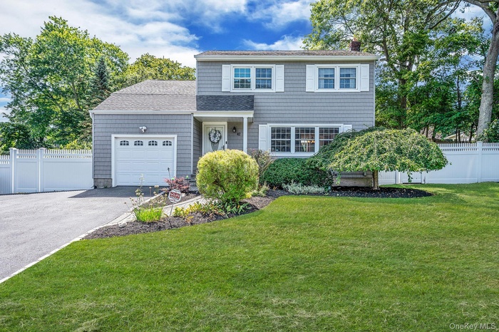 View of front of house featuring a garage, asphalt driveway, a chimney, and a shingled roof