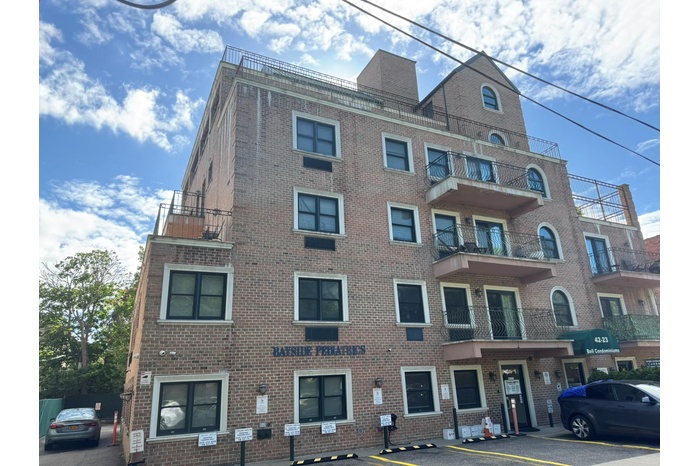 View of apartment building / complex featuring uncovered parking