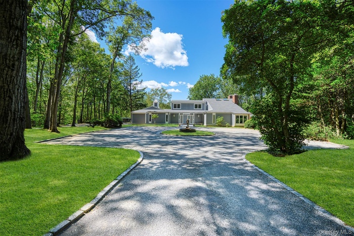 View of front of house featuring curved driveway, a chimney, a porch, and a front lawn
